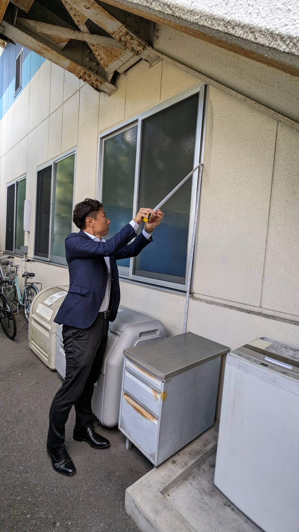 協成産業株式会社様の老朽化したオフィスをメジャーで測る豊田市のメディクロホーム伊藤社長